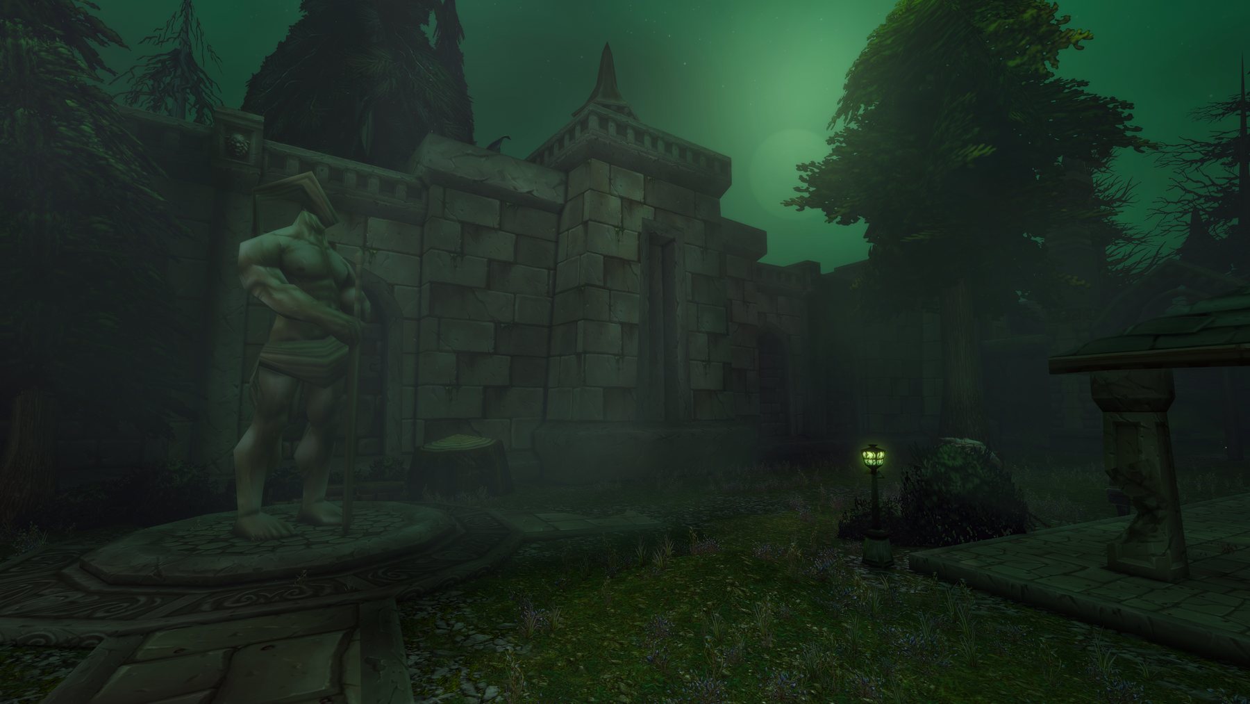 A ruined stone gatehouse under a sickly green sky, with a weathered statue on a plinth in the foreground and a single lit lamp on the overgrown path.